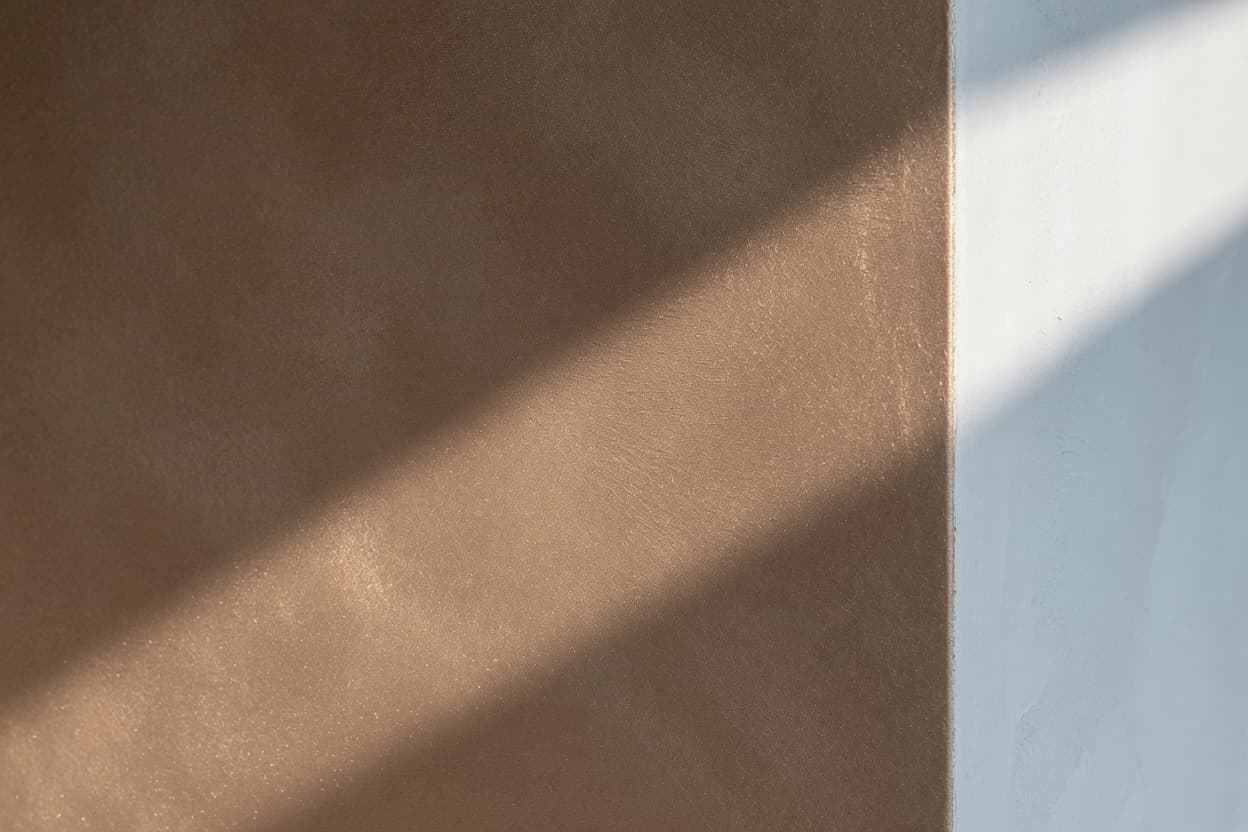 Metallic bronze suede wall finish meeting a sharp white plaster corner